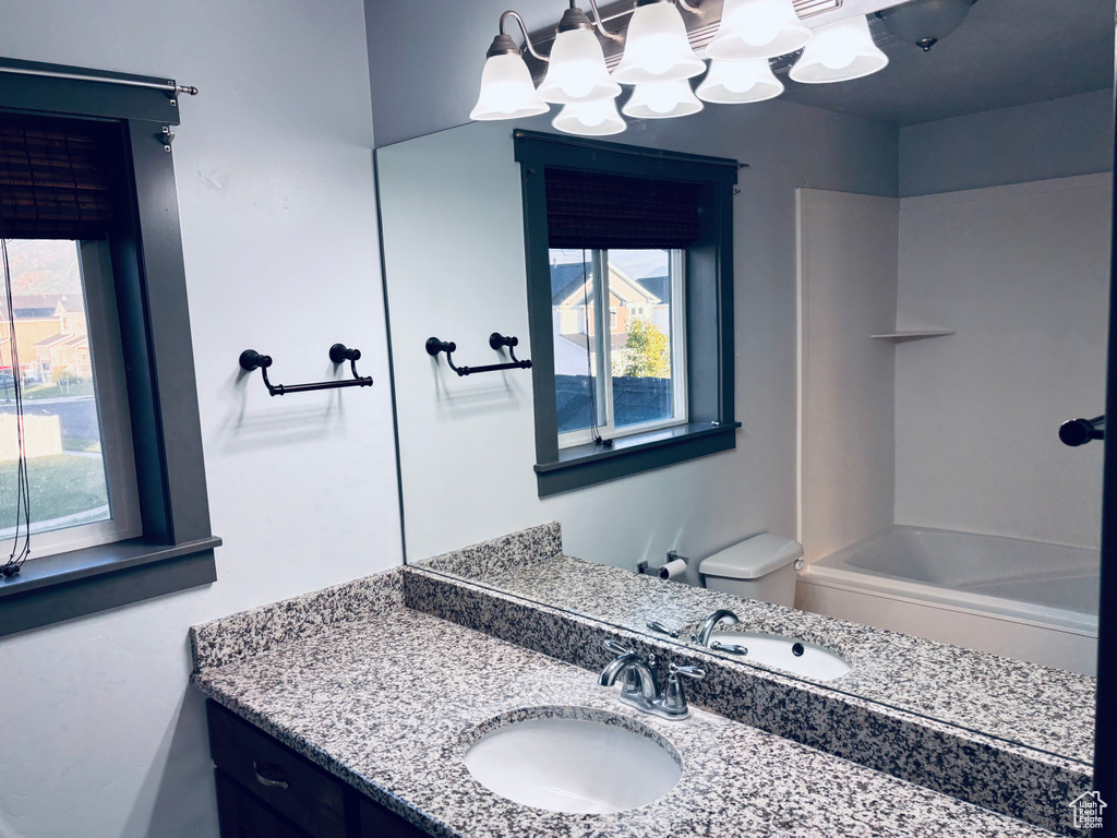 Full bathroom featuring healthy amount of natural light, vanity, toilet, and bathing tub / shower combination