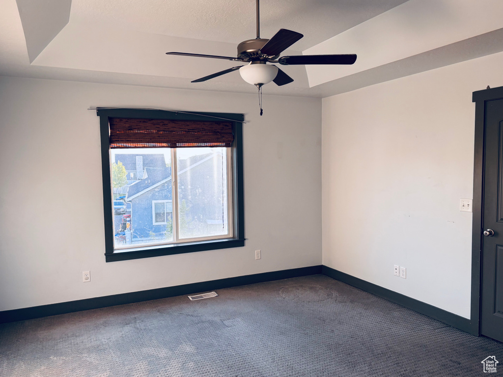 Carpeted spare room featuring a ceiling fan and baseboards