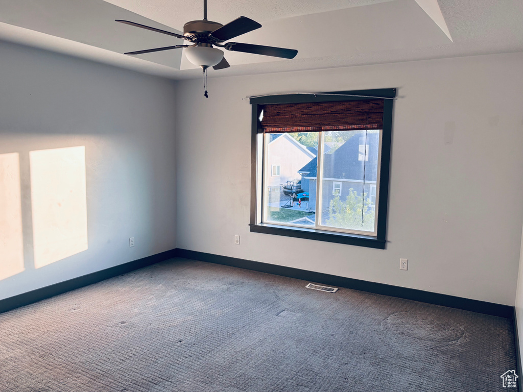 Carpeted spare room featuring baseboards, a ceiling fan, and a textured ceiling