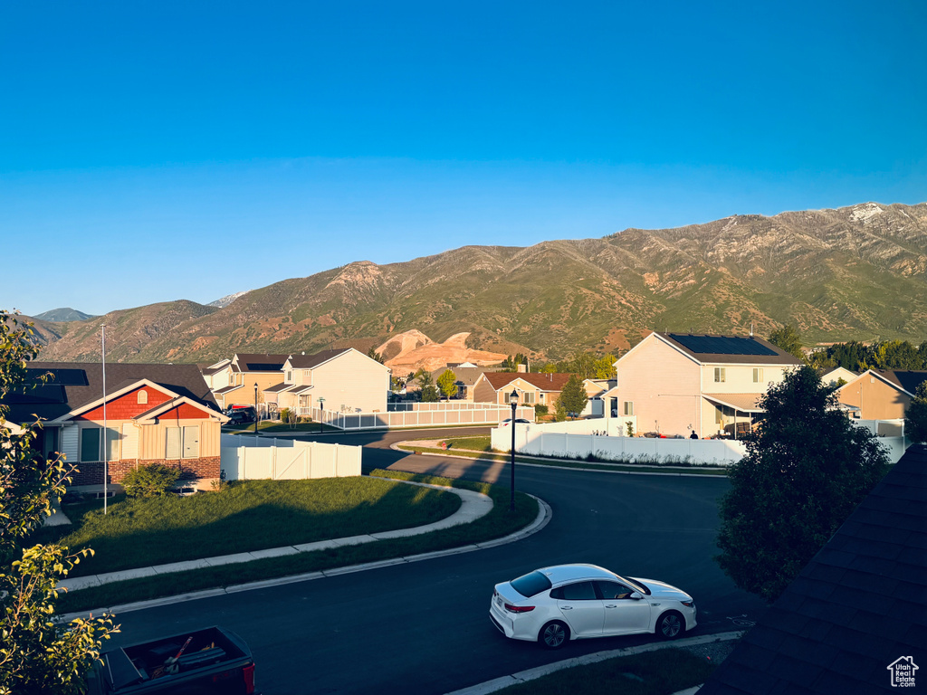 View of asphalt street with sidewalks, a residential view, a mountain view, and street lighting