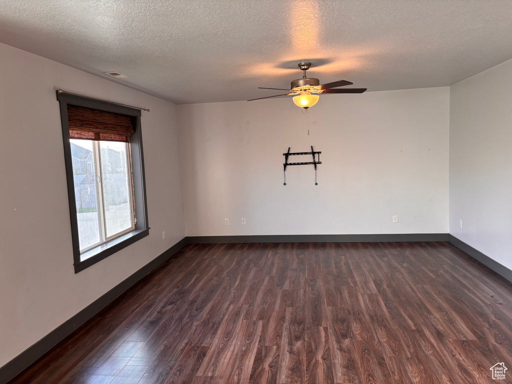 Spare room featuring dark wood finished floors, ceiling fan, a textured ceiling, and baseboards