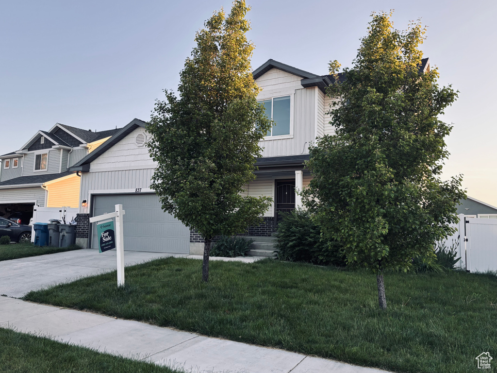 View of front facade featuring board and batten siding, driveway, and a garage