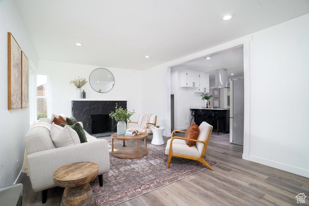 Living room featuring baseboards, recessed lighting, wood finished floors, and a fireplace
