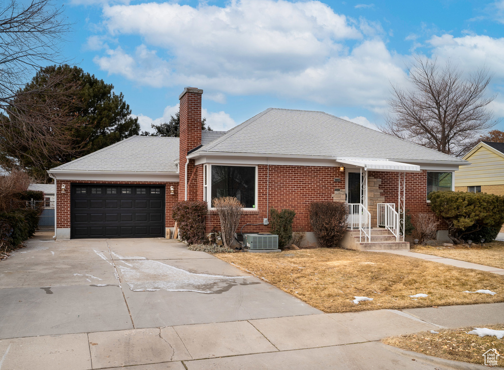 Single story home featuring an attached garage, brick siding, central air condition unit, and concrete driveway