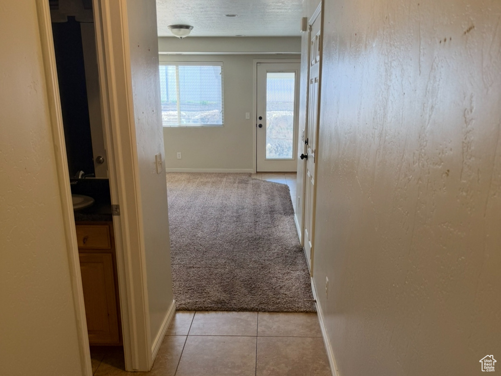 Hall with light tile patterned flooring and baseboards