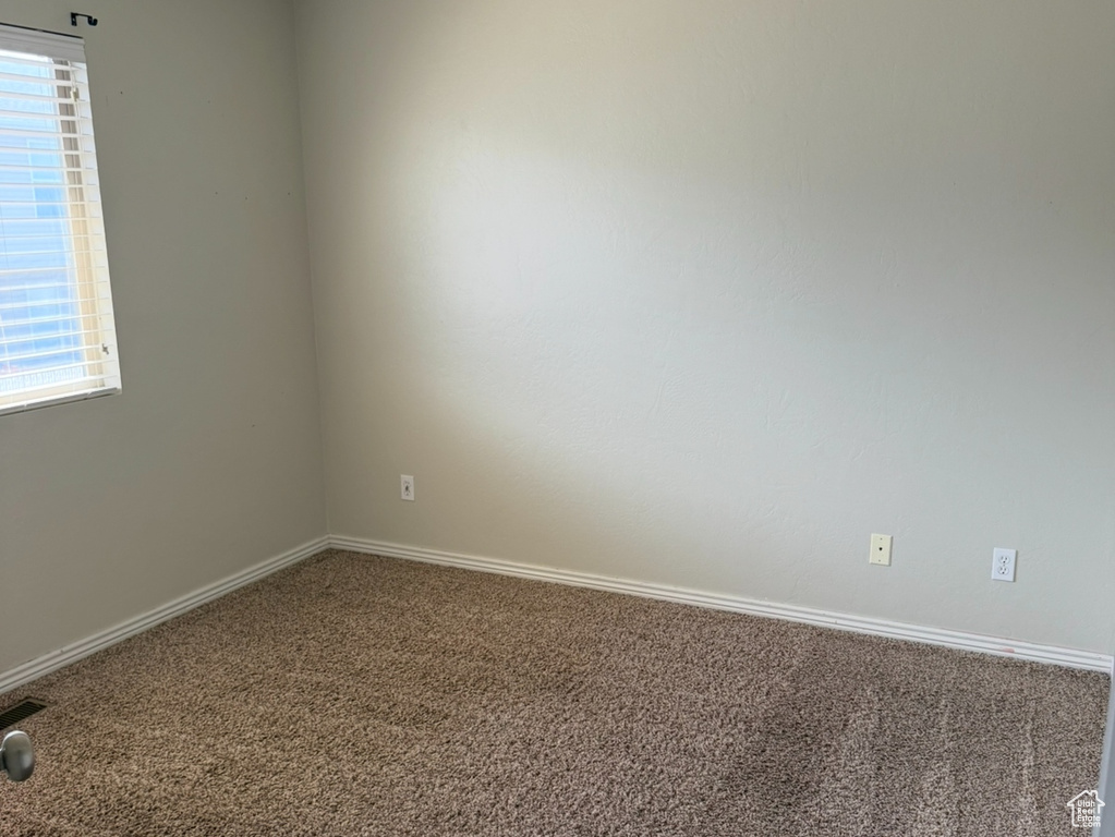 Carpeted spare room featuring baseboards