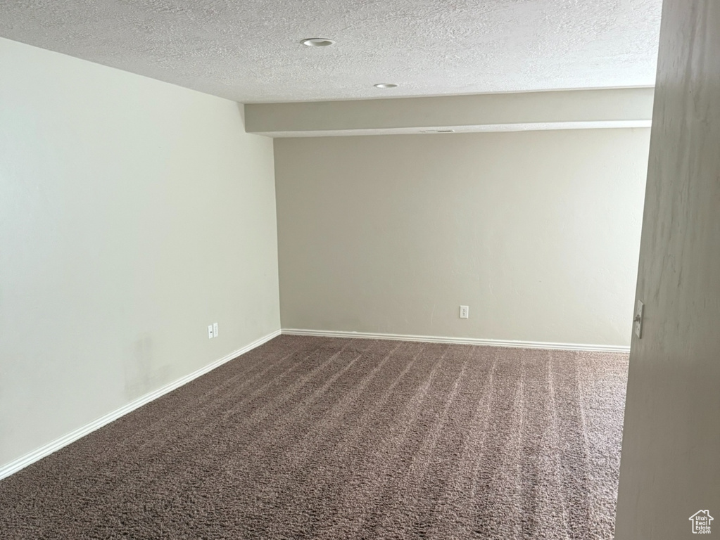 Spare room with carpet floors, a textured ceiling, and baseboards