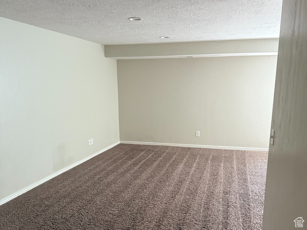 Carpeted empty room with baseboards and a textured ceiling
