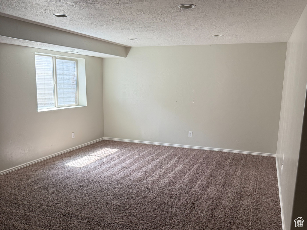 Spare room with baseboards, carpet floors, and a textured ceiling
