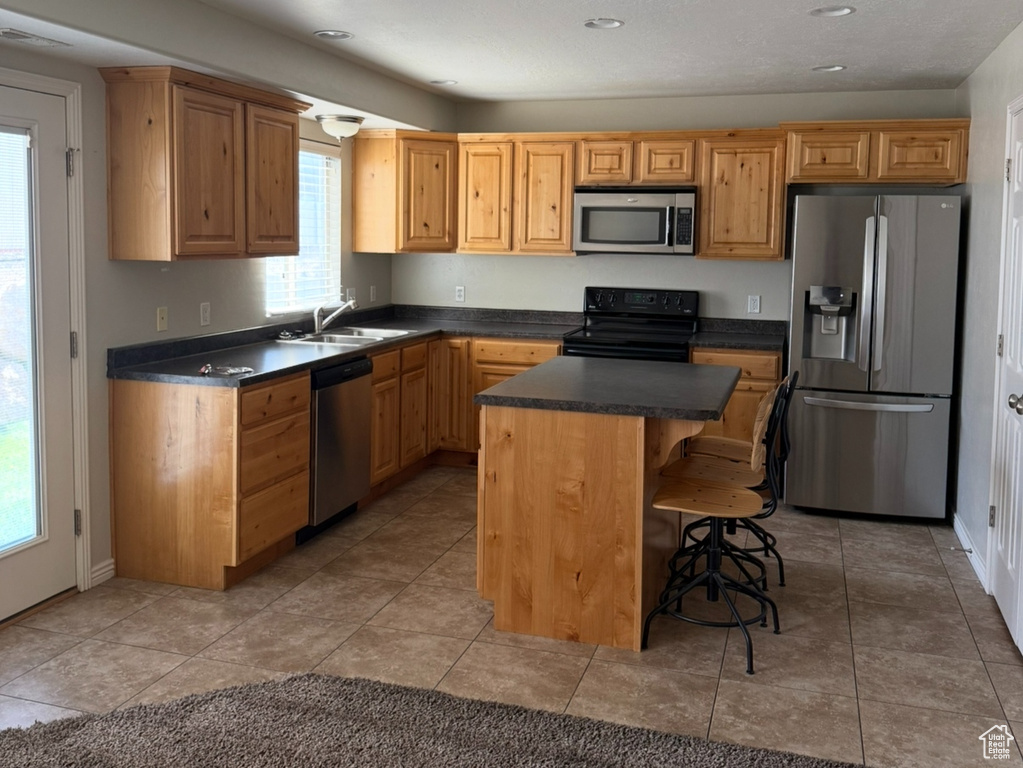 Kitchen featuring appliances with stainless steel finishes, healthy amount of natural light, dark countertops, a breakfast bar area, and a textured ceiling
