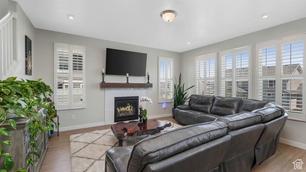Living area with healthy amount of natural light, wood finished floors, a brick fireplace, and recessed lighting