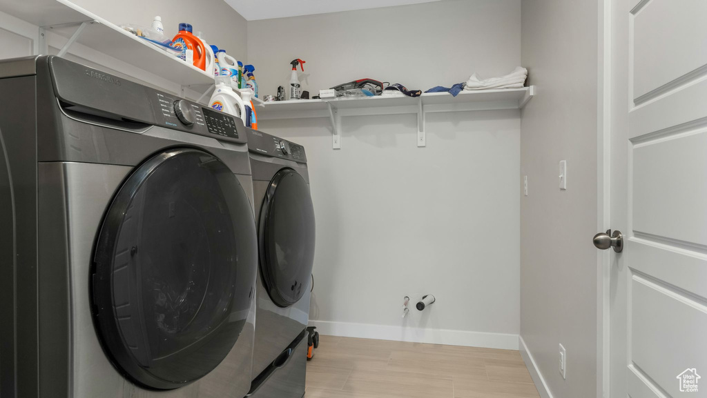 Laundry area with separate washer and dryer, light wood-style floors, and baseboards