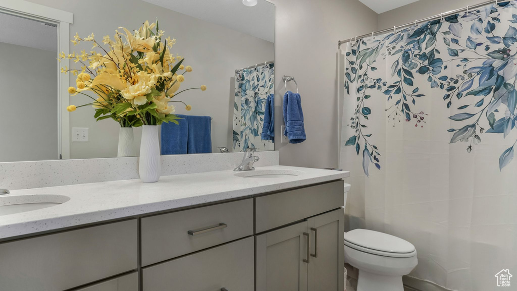 Full bath with double vanity, toilet, and shower / bath combination with curtain