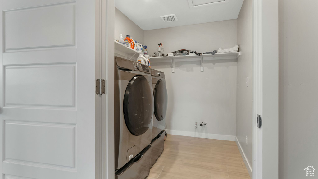 Laundry room with washing machine and dryer, light wood-type flooring, and baseboards