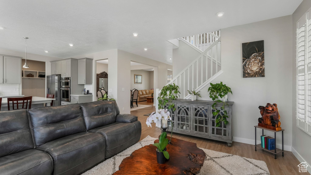 Living room featuring stairs, light wood finished floors, baseboards, and recessed lighting
