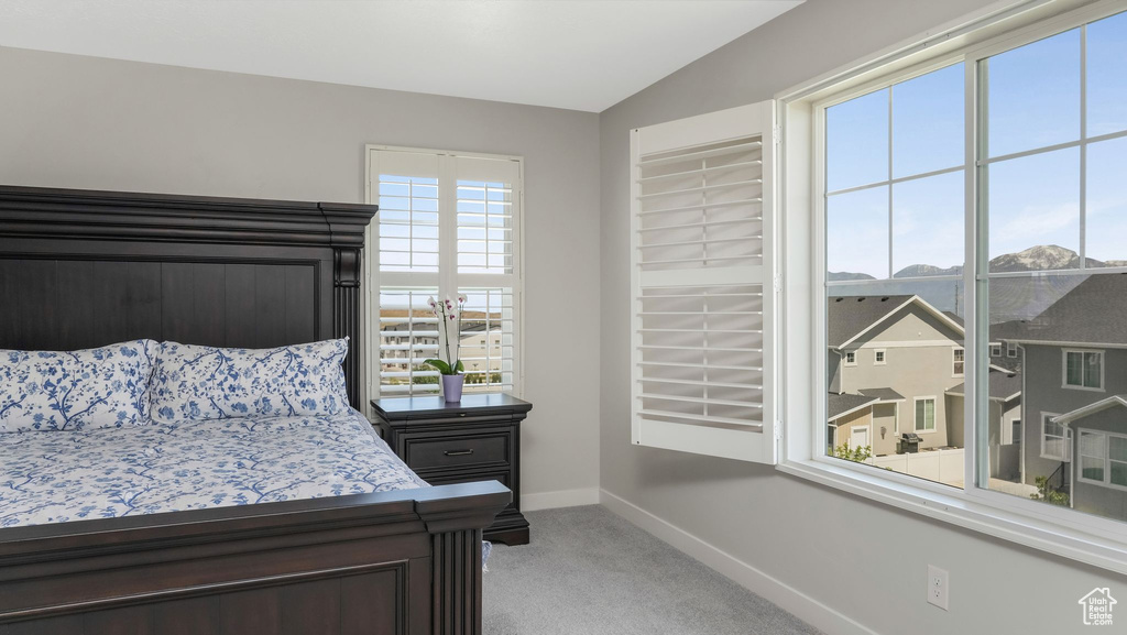 Bedroom featuring baseboards, light colored carpet, and vaulted ceiling
