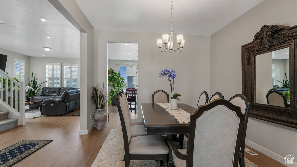 Dining room featuring stairs, baseboards, wood finished floors, a chandelier, and recessed lighting