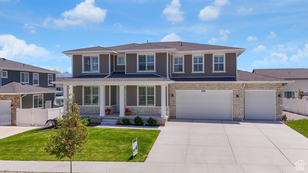 View of front of home featuring covered porch, stone siding, concrete driveway, and an attached garage
