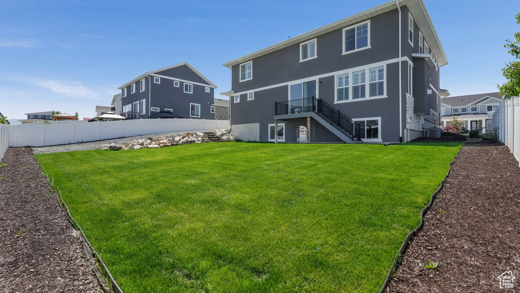 Rear view of house with stairs, cooling unit, and stucco siding