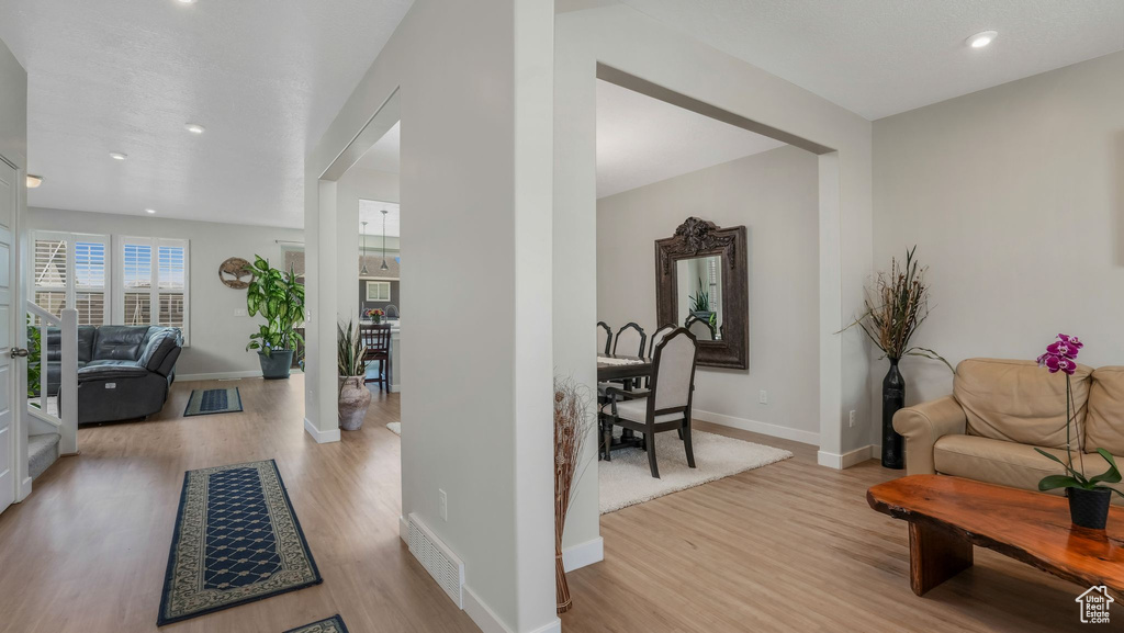 Living room with light wood finished floors, baseboards, recessed lighting, and arched walkways