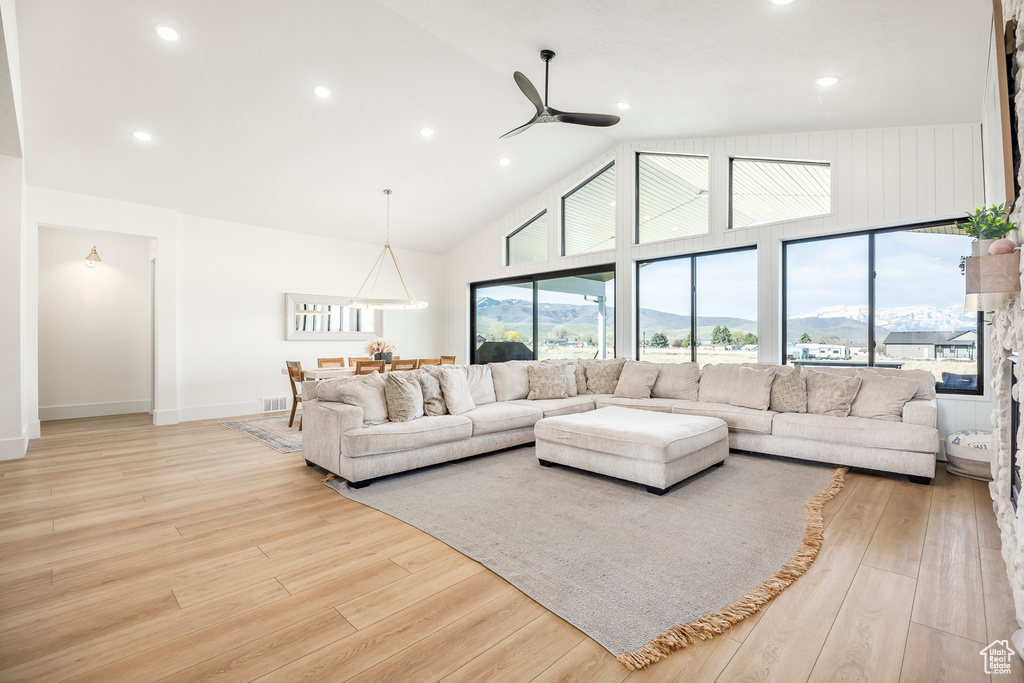 Living room featuring high vaulted ceiling, recessed lighting, a ceiling fan, and light wood-type flooring