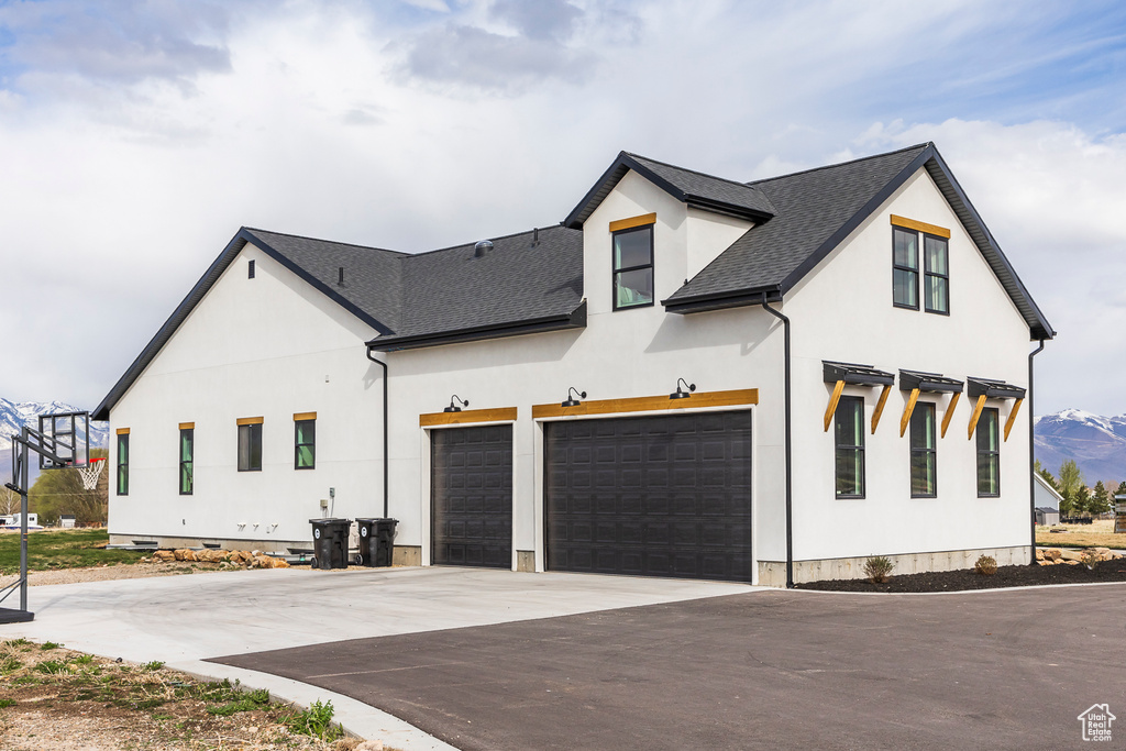 View of side of property featuring stucco siding, driveway, and a garage
