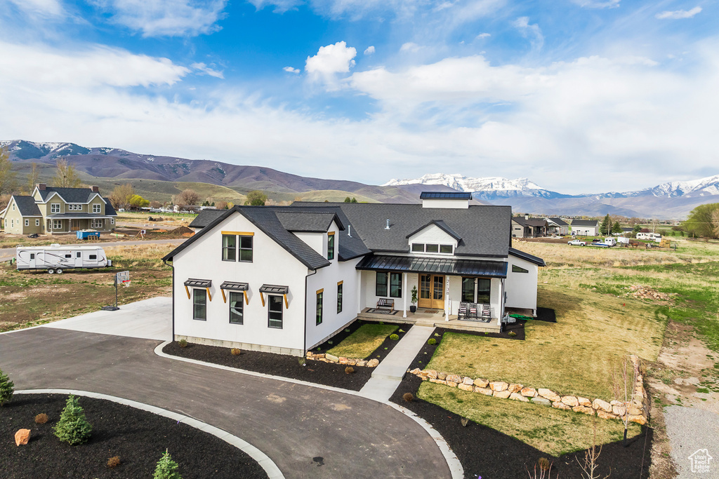 Back of property featuring a shingled roof, curved driveway, a mountain view, and stucco siding