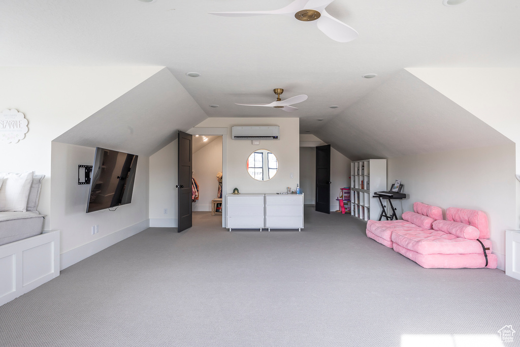 Bonus room featuring a wall mounted AC, vaulted ceiling, light colored carpet, and ceiling fan
