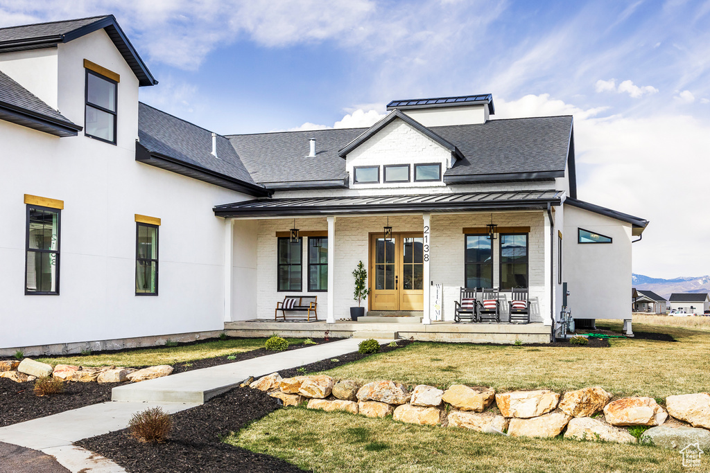 Rear view of property with a yard, a standing seam roof, covered porch, brick siding, and metal roof