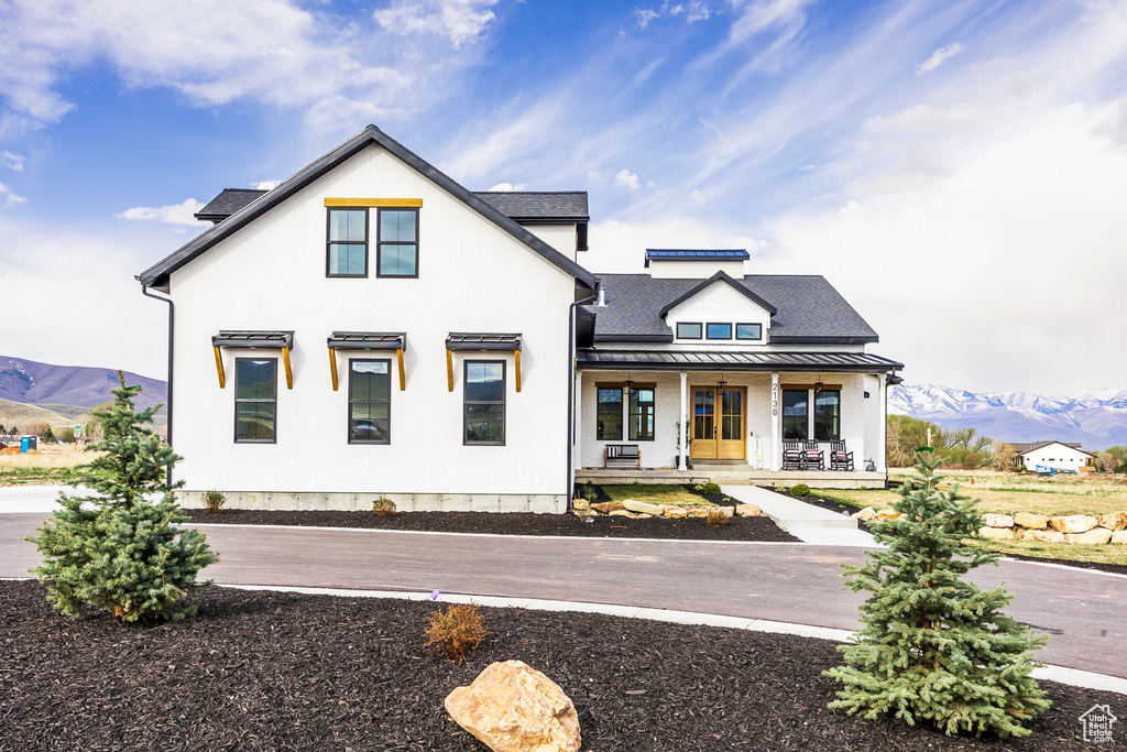 Modern farmhouse style home with a porch, a standing seam roof, a mountain view, and stucco siding