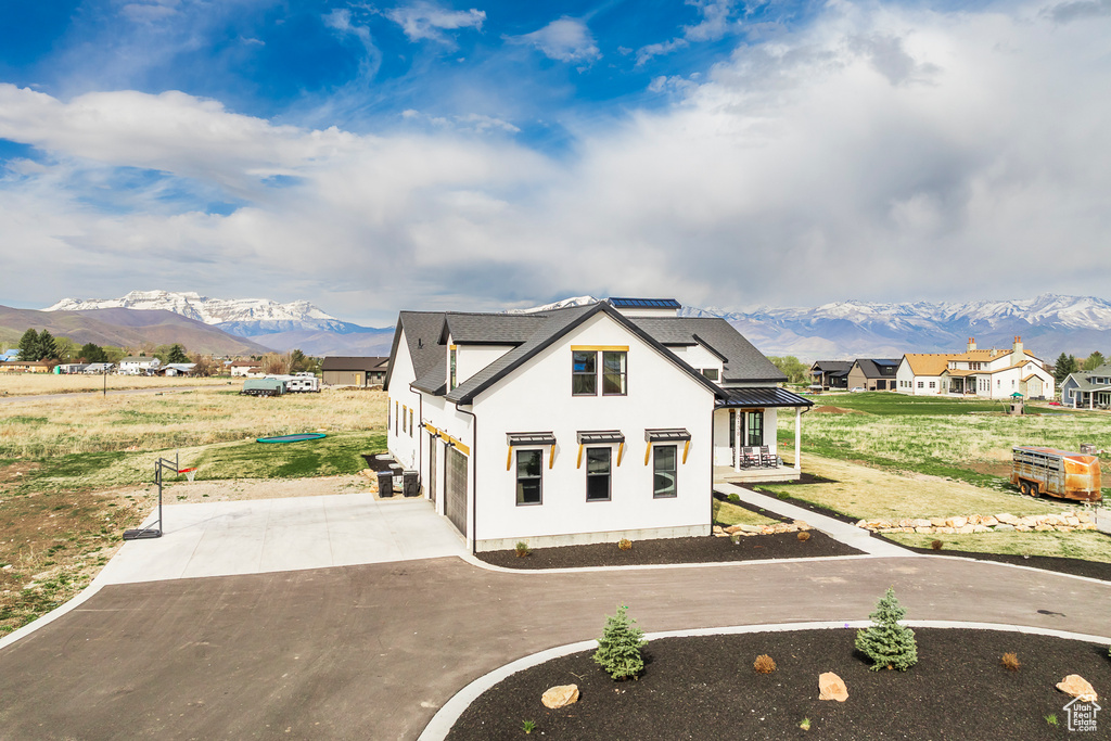 View of front facade with metal roof, a front yard, concrete driveway, and a mountain view