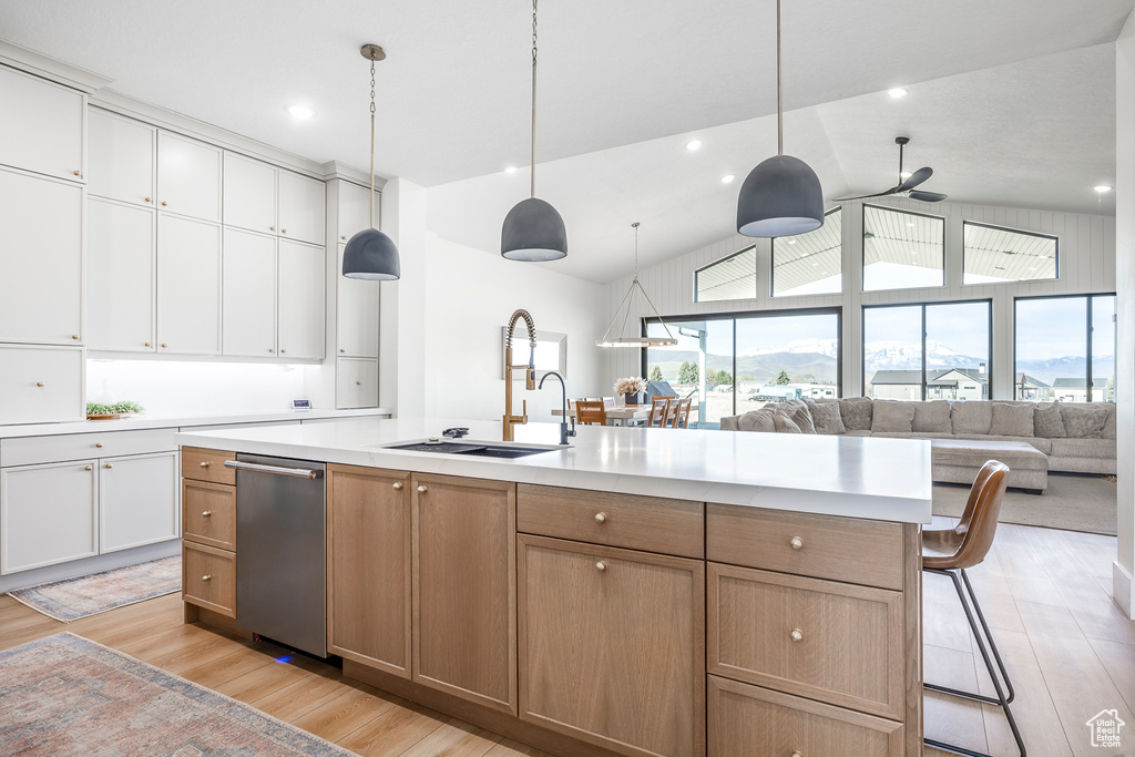 Kitchen with light countertops, light wood-style floors, open floor plan, and stainless steel dishwasher