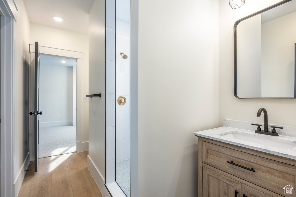 Bathroom featuring wood finished floors, recessed lighting, vanity, and a tile shower