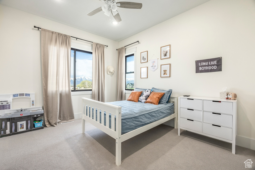 Bedroom with light colored carpet, ceiling fan, and baseboards