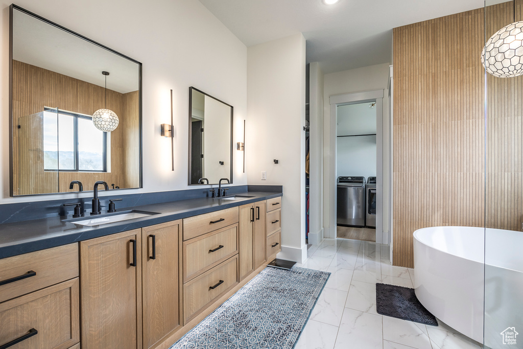 Bathroom with double vanity, a soaking tub, marble finish floor, and a sink