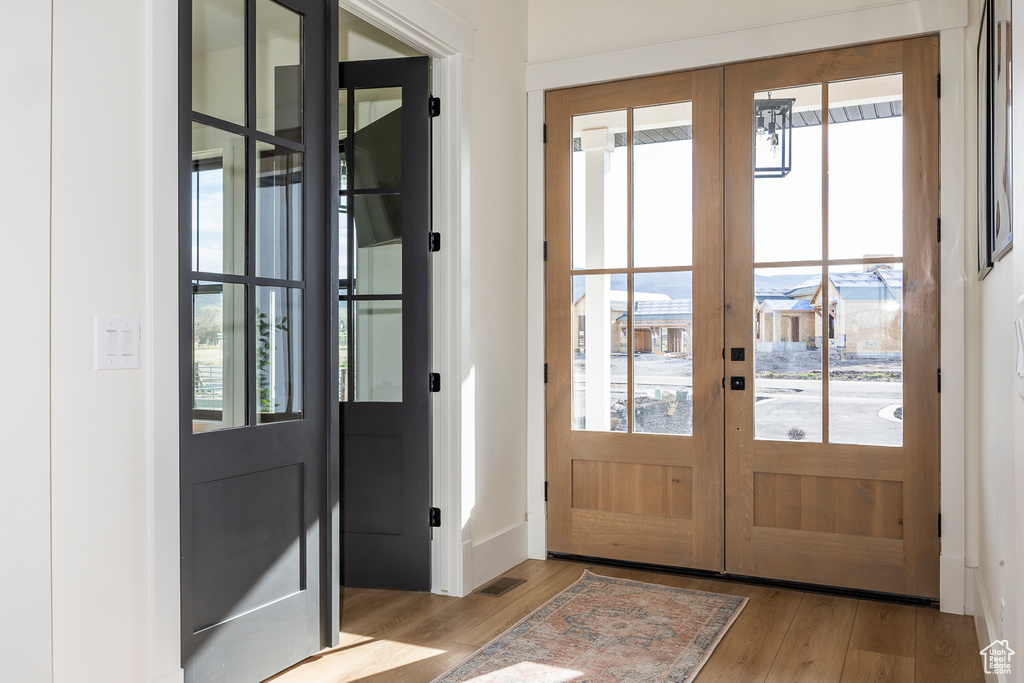 Doorway to outside featuring wood finished floors, visible vents, baseboards, and french doors