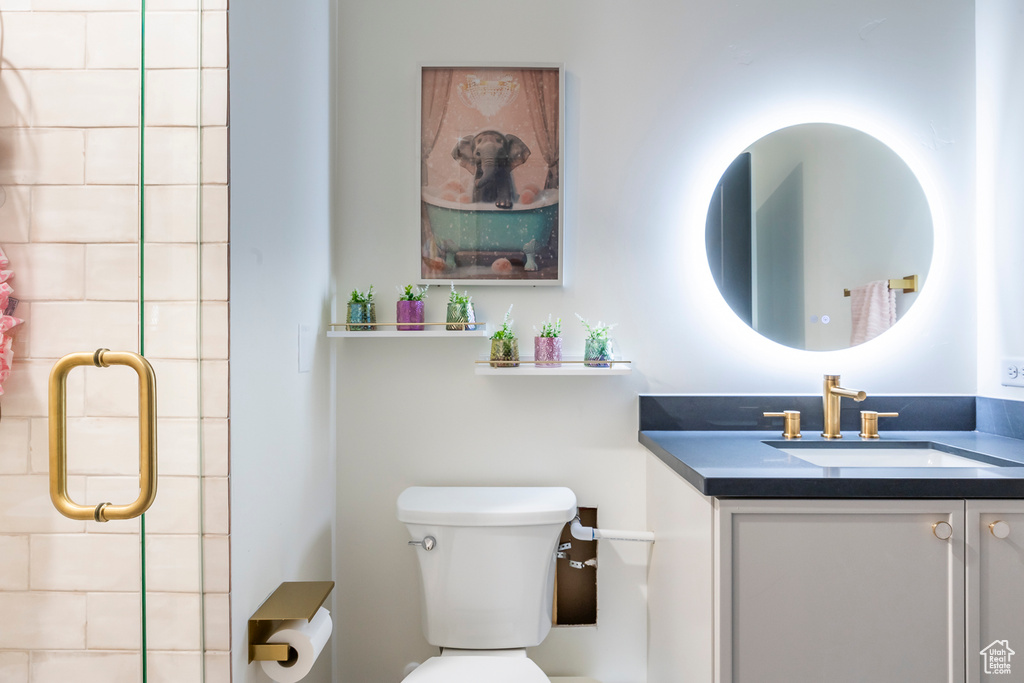 Bathroom featuring tiled shower, vanity, and toilet