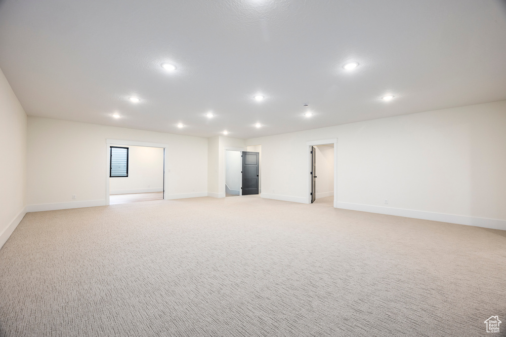Empty room featuring light colored carpet, baseboards, and recessed lighting