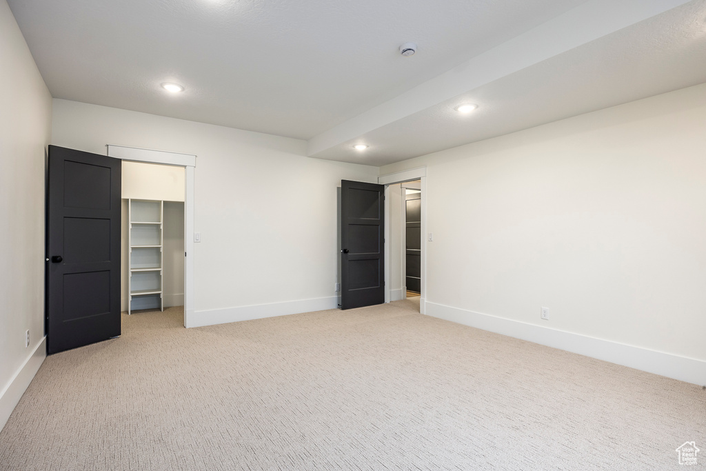 Unfurnished bedroom featuring recessed lighting, a spacious closet, baseboards, and light carpet