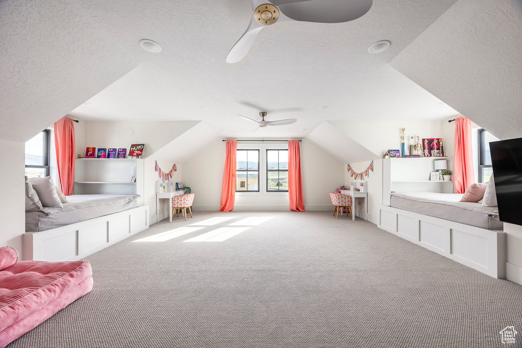 Playroom with vaulted ceiling, ceiling fan, carpet floors, and a textured ceiling