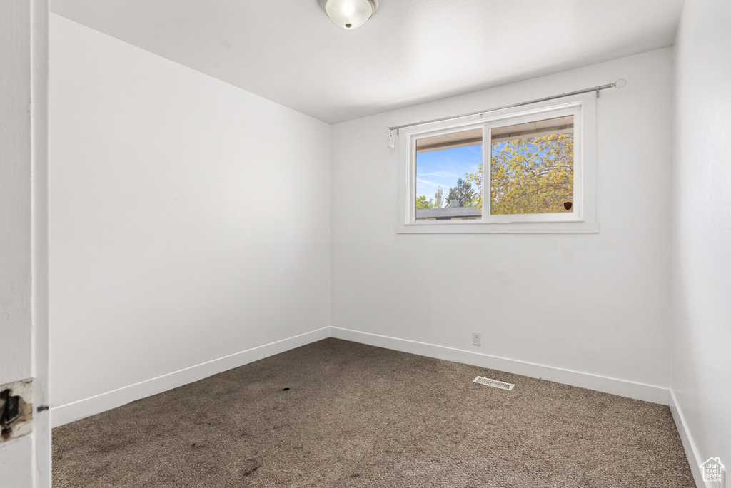 Unfurnished room featuring dark colored carpet and baseboards