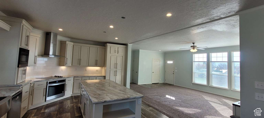 Kitchen featuring wall chimney exhaust hood, black appliances, a kitchen island, a ceiling fan, and open shelves