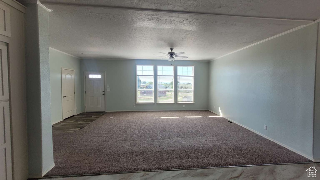Foyer featuring crown molding, ceiling fan, baseboards, carpet flooring, and a textured ceiling