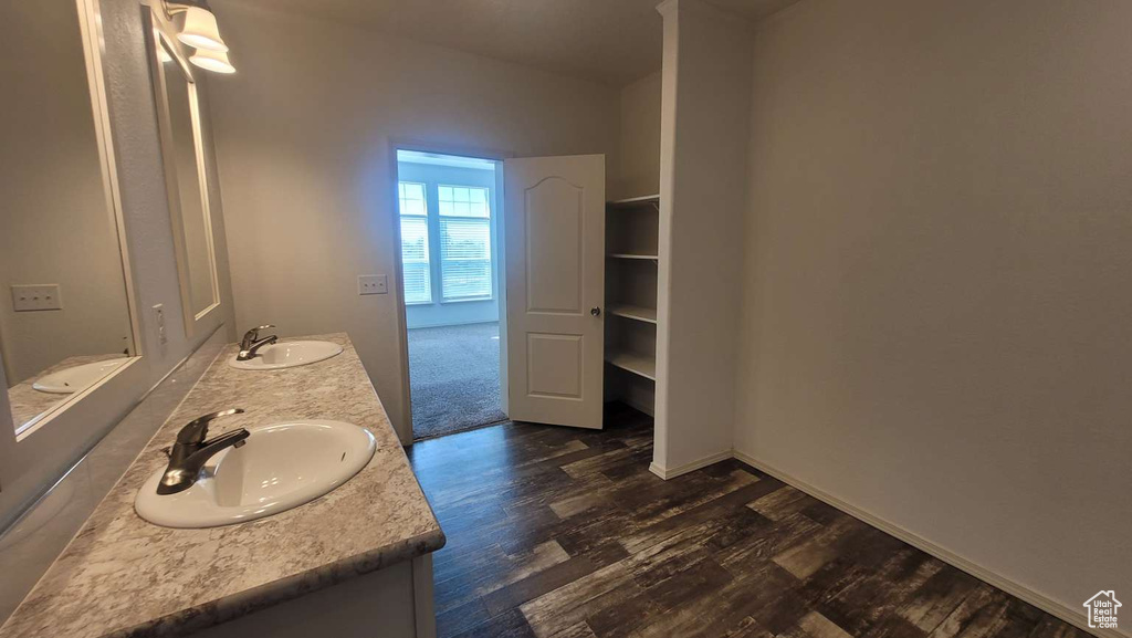 Bathroom featuring double vanity, wood finished floors, and baseboards