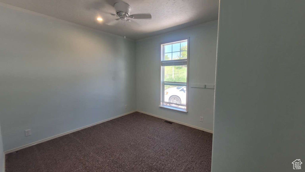 Spare room with dark colored carpet, a ceiling fan, and baseboards
