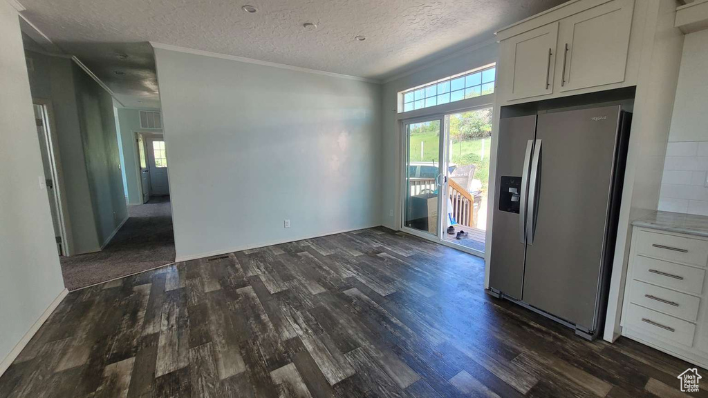 Kitchen featuring stainless steel refrigerator with ice dispenser, dark wood finished floors, white cabinets, crown molding, and a textured ceiling