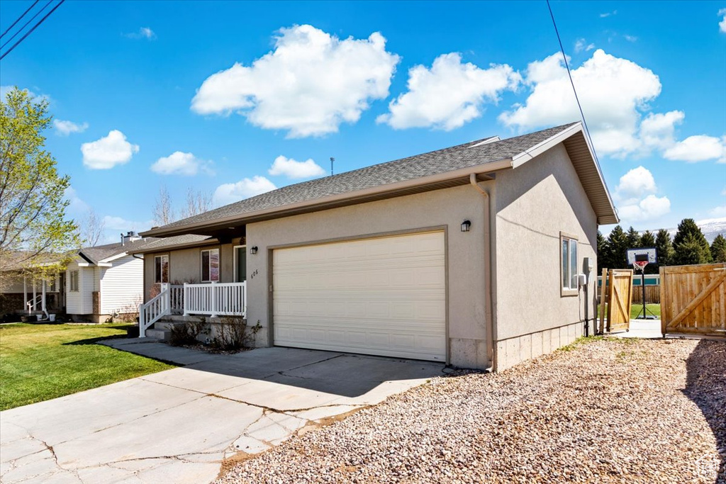 View of front facade featuring driveway, fence, a garage, a front yard, and stucco siding