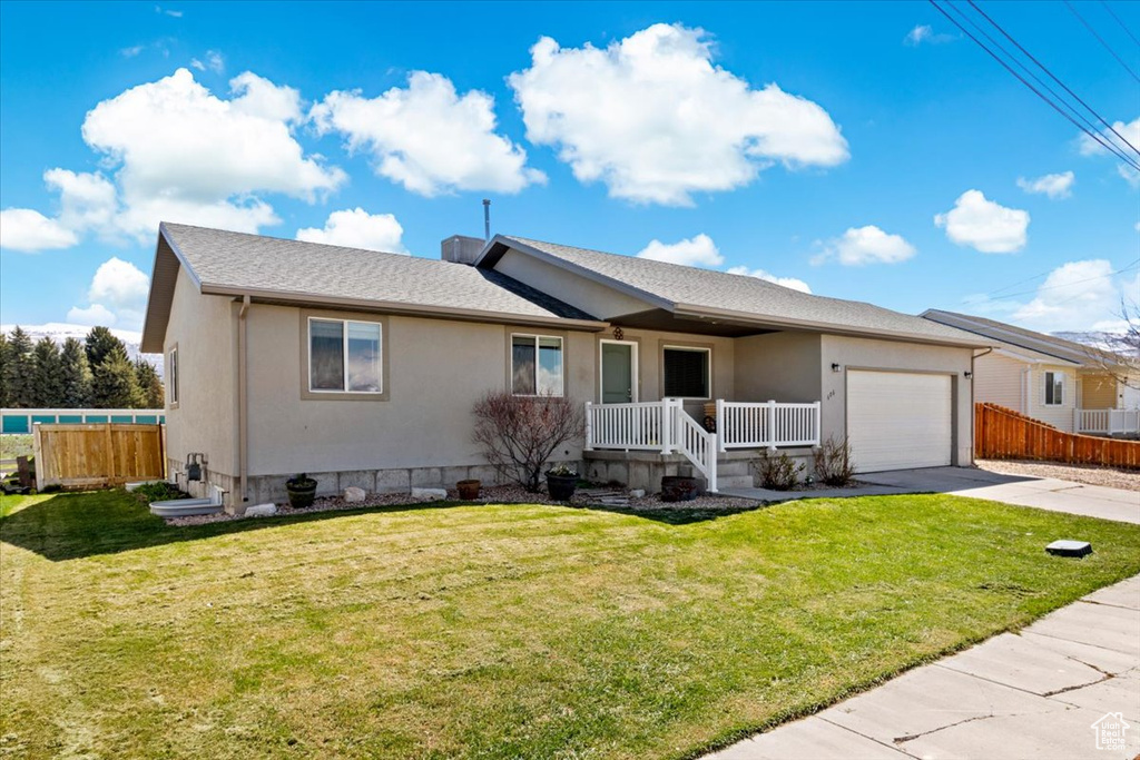 Single story home with an attached garage, concrete driveway, covered porch, and fence