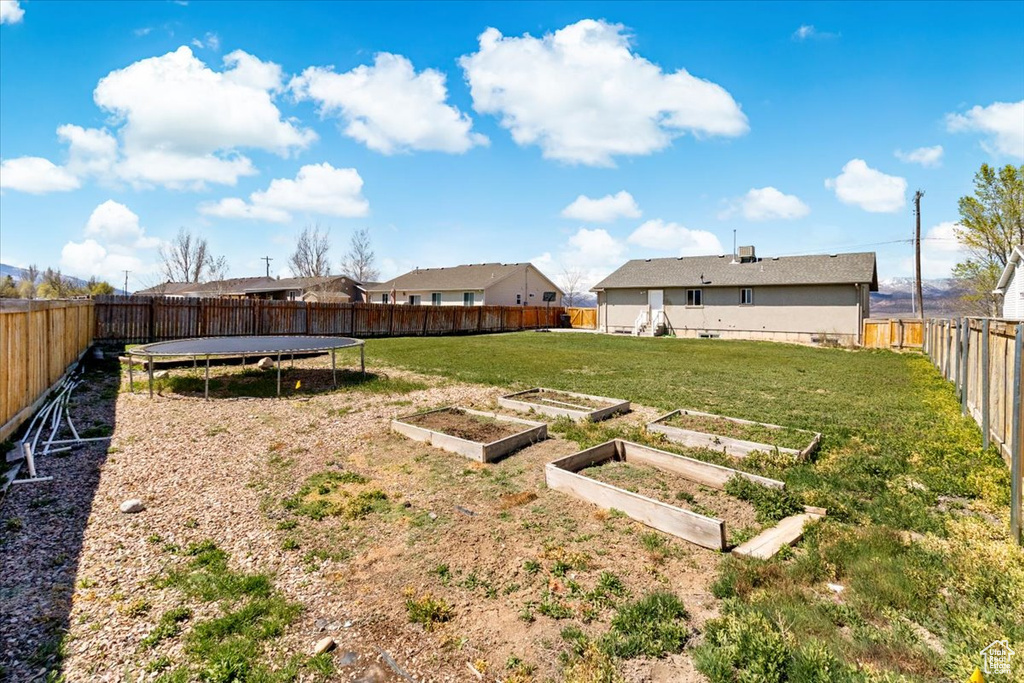 View of yard featuring a fenced backyard, a garden, and a trampoline