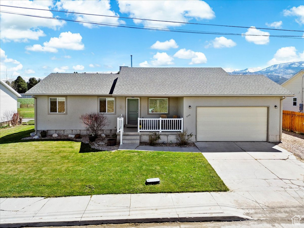 Ranch-style home featuring a front lawn, stucco siding, driveway, a porch, and a garage